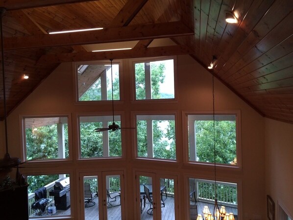 Una habitación amplia con ventanas grandes, ventilador de techo y vistas al exterior.
