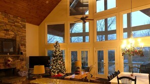 A spacious kitchen with a large island, a stone fireplace, and a Christmas tree.