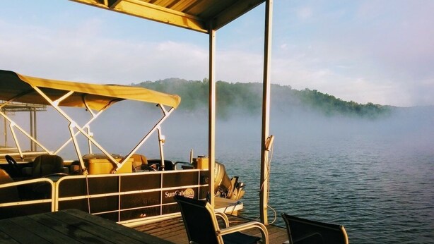 A boat deck with a covered seating area, a table, and a grill.