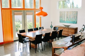 Un comedor moderno con una mesa de madera, sillas negras y un amplio ventanal con vistas a árboles.