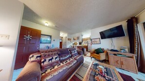 Ein gemütliches Wohnzimmer mit einer Couch, einem Fernseher und einem Holzkabinett.