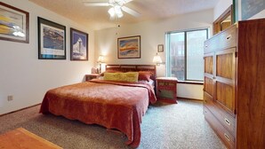 Ein Schlafzimmer mit einem großen Bett, einer hölzernen Kommode und einem Fenster mit Blick.