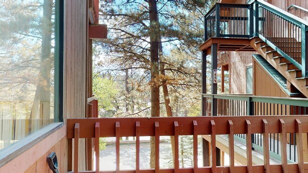 Eine Holzdiele mit einem Balkon, einer Treppe und Blick auf Bäume.