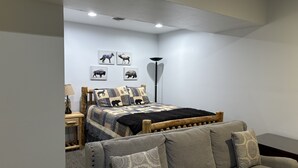 Ein Schlafzimmer mit einem Bett, einem Nachttisch, einer Lampe, einer Stehlampe und einem Sofa.