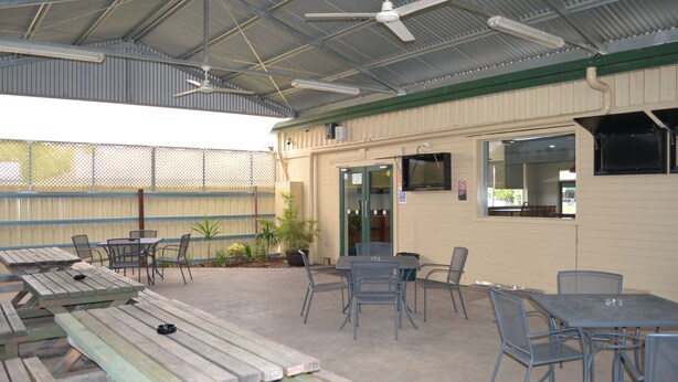 An outdoor patio area with multiple tables and chairs, a ceiling fan, and a covered entrance.