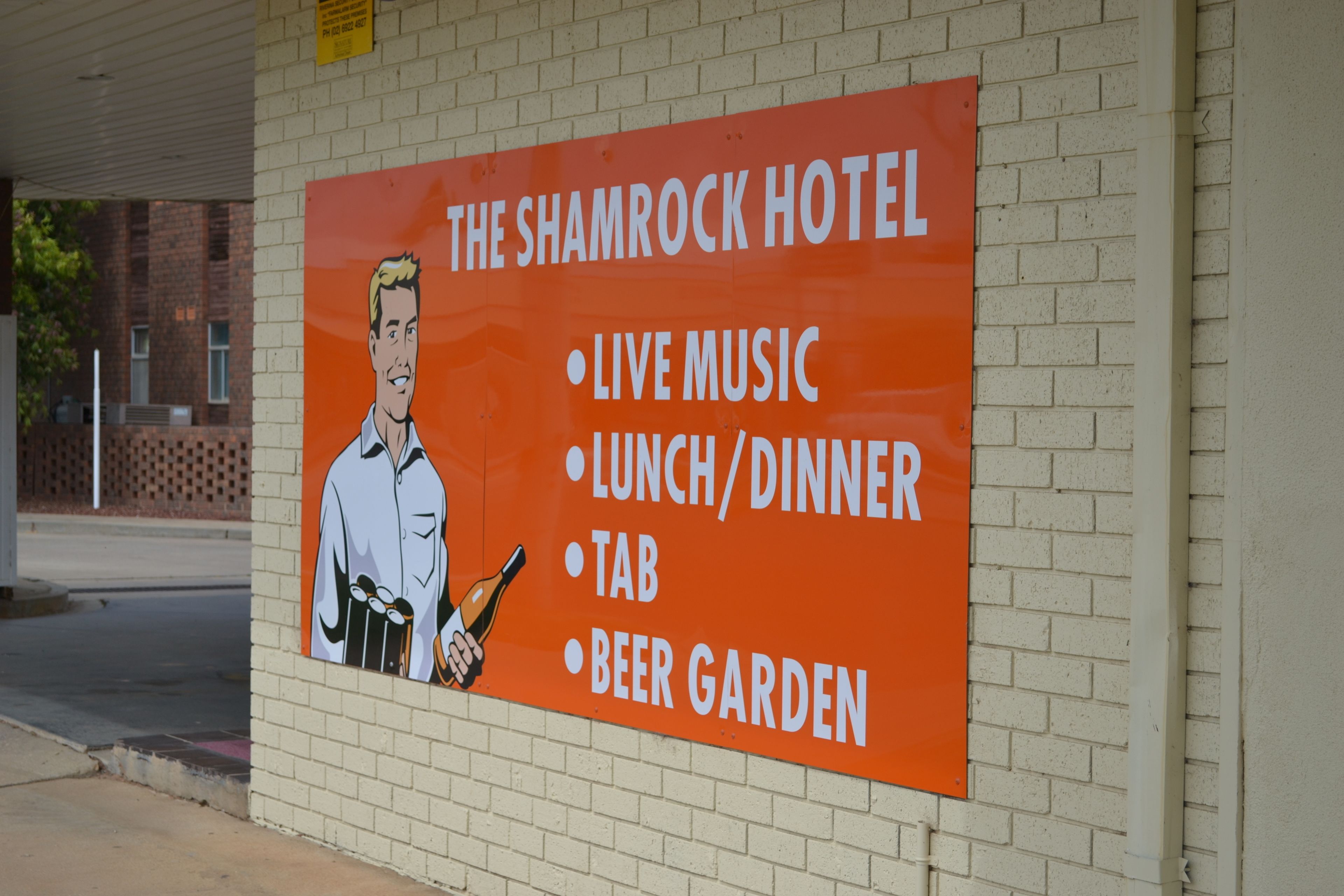 Un cartel del Hotel Shamrock que anuncia servicios como música en vivo, almuerzo/cena, pestaña de crédito y un jardín de cerveza.