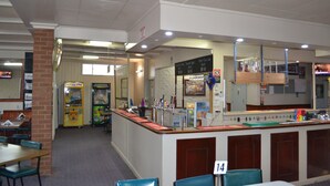 A restaurant with a counter, seating area, and vending machines.
