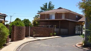 A two-story house with a brick exterior, a covered porch, and a gated driveway.