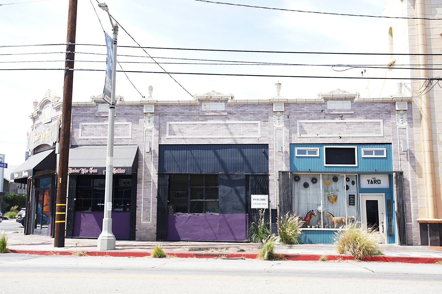 A building with a storefront labeled "Tattoo" and another labeled "The Yard."