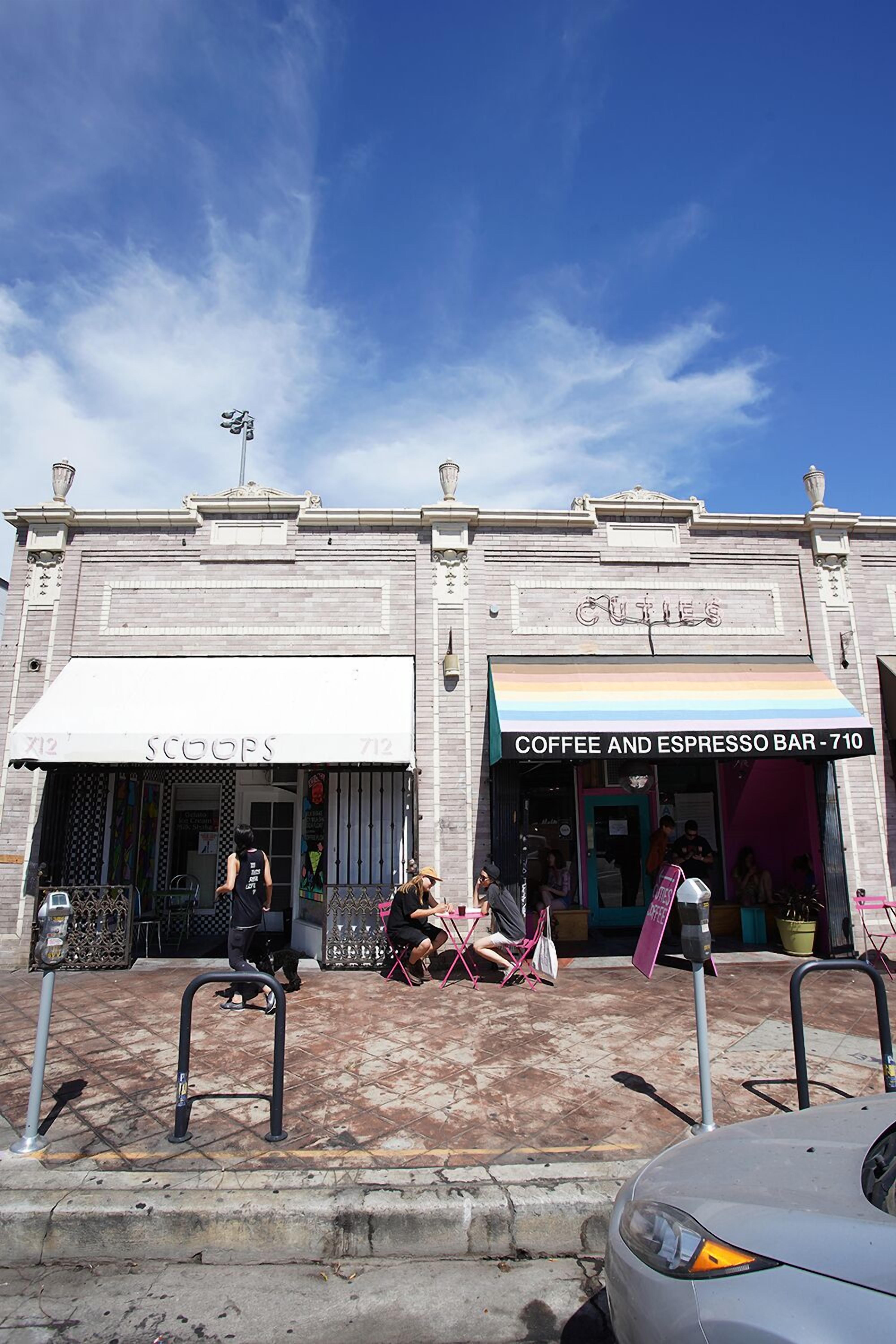 A building with a coffee and espresso bar, a store named 'SCOOPS', and a parking meter.