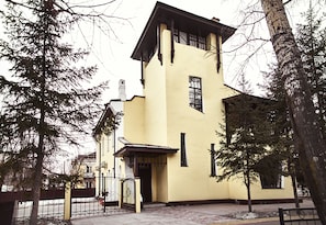A yellow building with a distinct architectural style, featuring a prominent entrance and a small window.