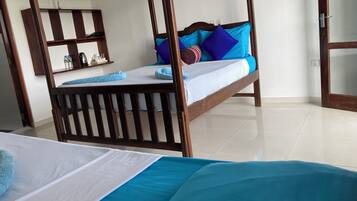 A room with a wooden four-poster bed, a small bedside table with a lamp, a mirror, and a shelf with toiletries.