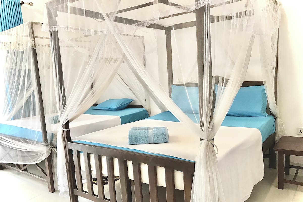 A four-poster bed with a canopy, two pillows, and a bedside table.