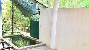 A covered outdoor area with a pool, wooden furniture, and a hanging light fixture. - Seashore Mirissa (Mirissa)