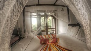 A bed with a striped blanket, a canopy, and a view of the outdoors through a window. - Seashore Mirissa (Mirissa)