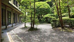 A traditional Japanese building with a gravel courtyard, surrounded by trees and greenery. - Hisaeya Ryokan (Fujioka)