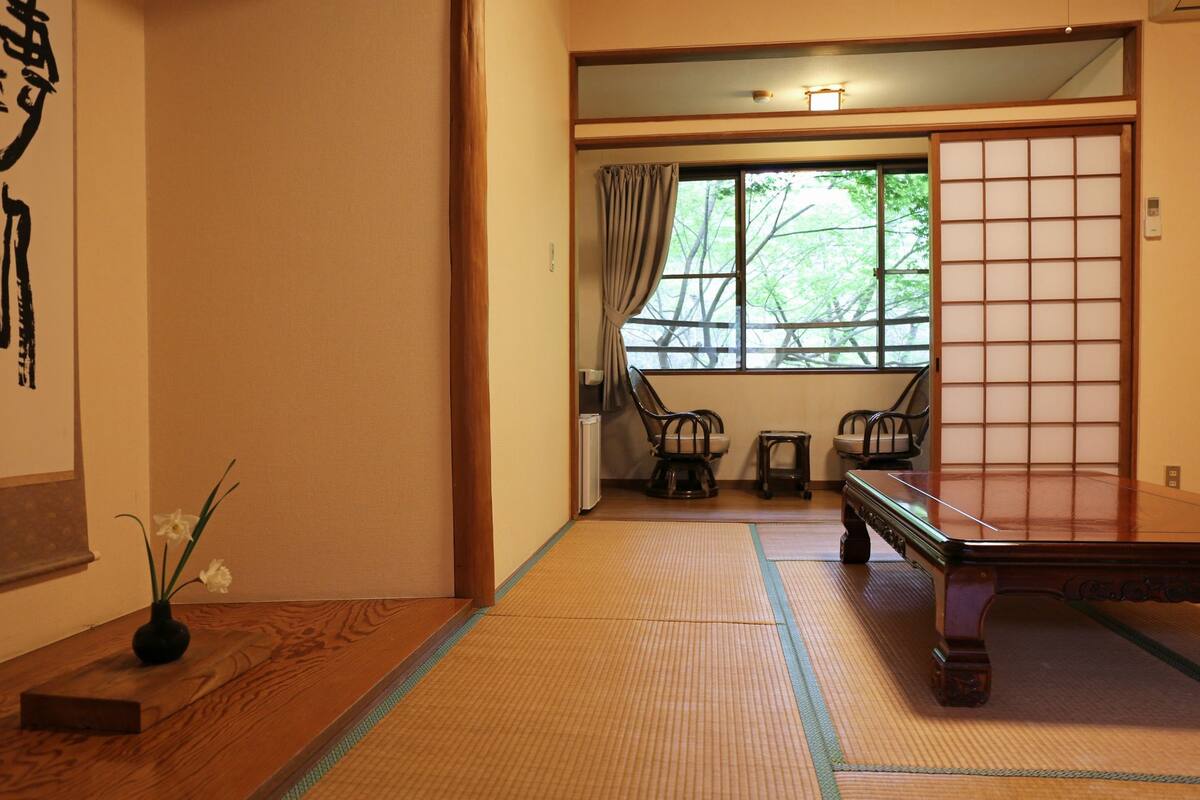 A traditional Japanese room with tatami flooring, a low table, and a sliding door.