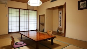A traditional Japanese room with tatami flooring, a wooden table, and sliding doors. - Hisaeya Ryokan (Fujioka)