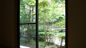 A large window with a view of a forested area. - Hisaeya Ryokan (Fujioka)