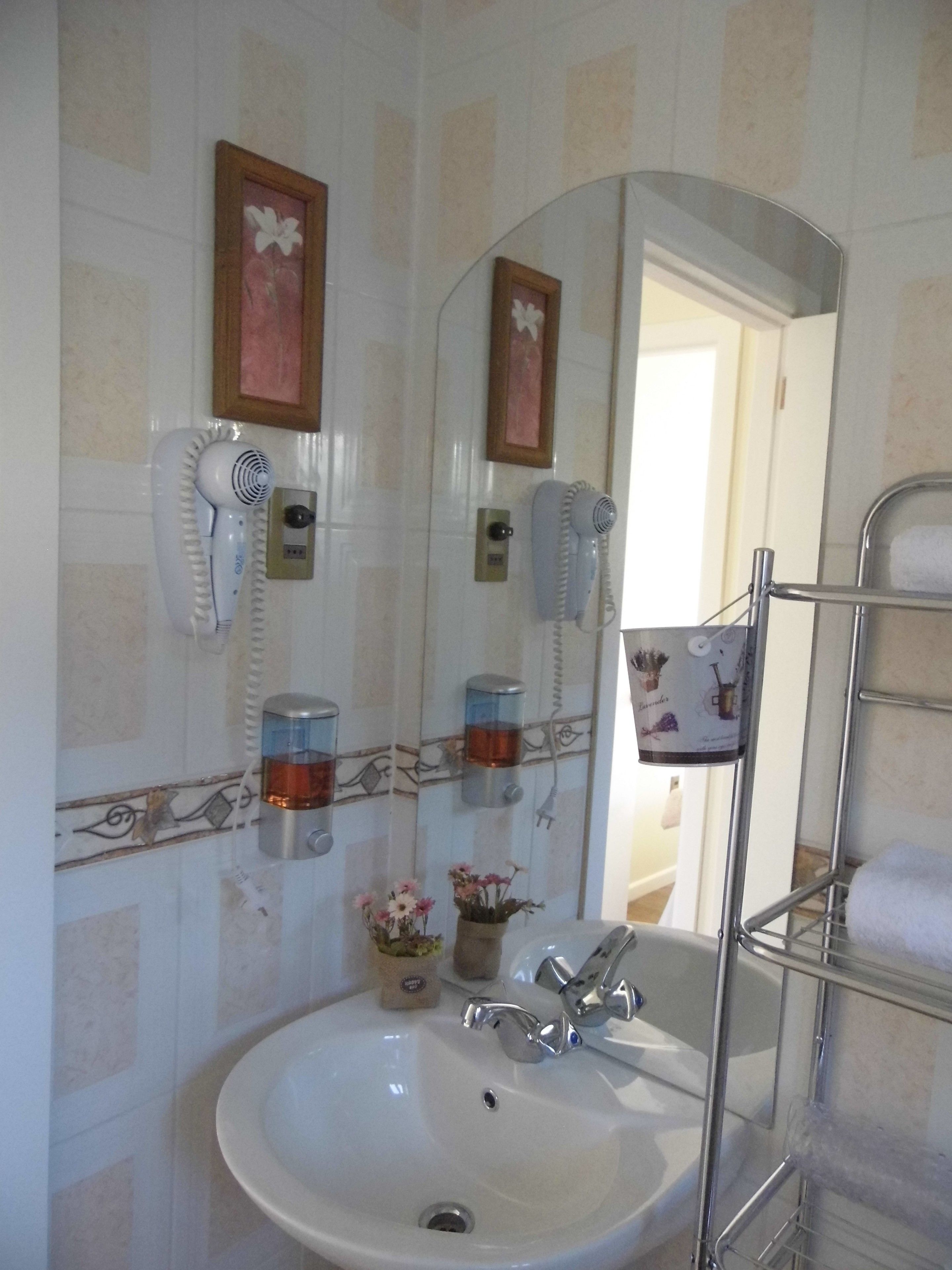 Une salle de bain équipée d’un lavabo, de deux sèche-cheveux, d’un miroir et d’un porte-serviettes.
