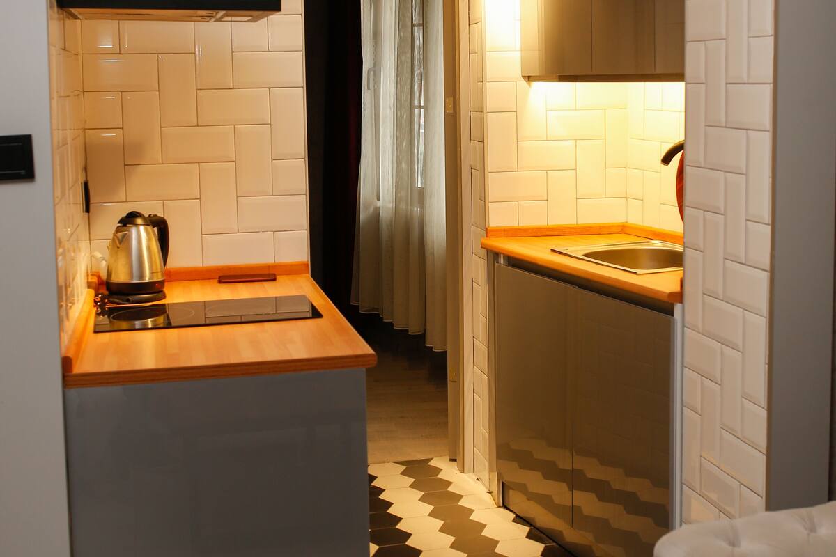 A compact kitchen with a built-in stove, a sink, and a black range hood.
