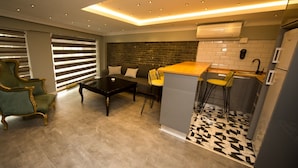 A modern kitchen with a bar area, a dining set, and a green armchair. - Hermes Park Hotel Sisli (Istanbul)