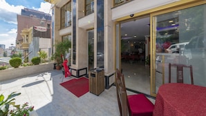 A hotel entrance with a glass door, a red carpet, and a small outdoor seating area with a table and chairs. - Hermes Park Hotel Sisli (Istanbul)