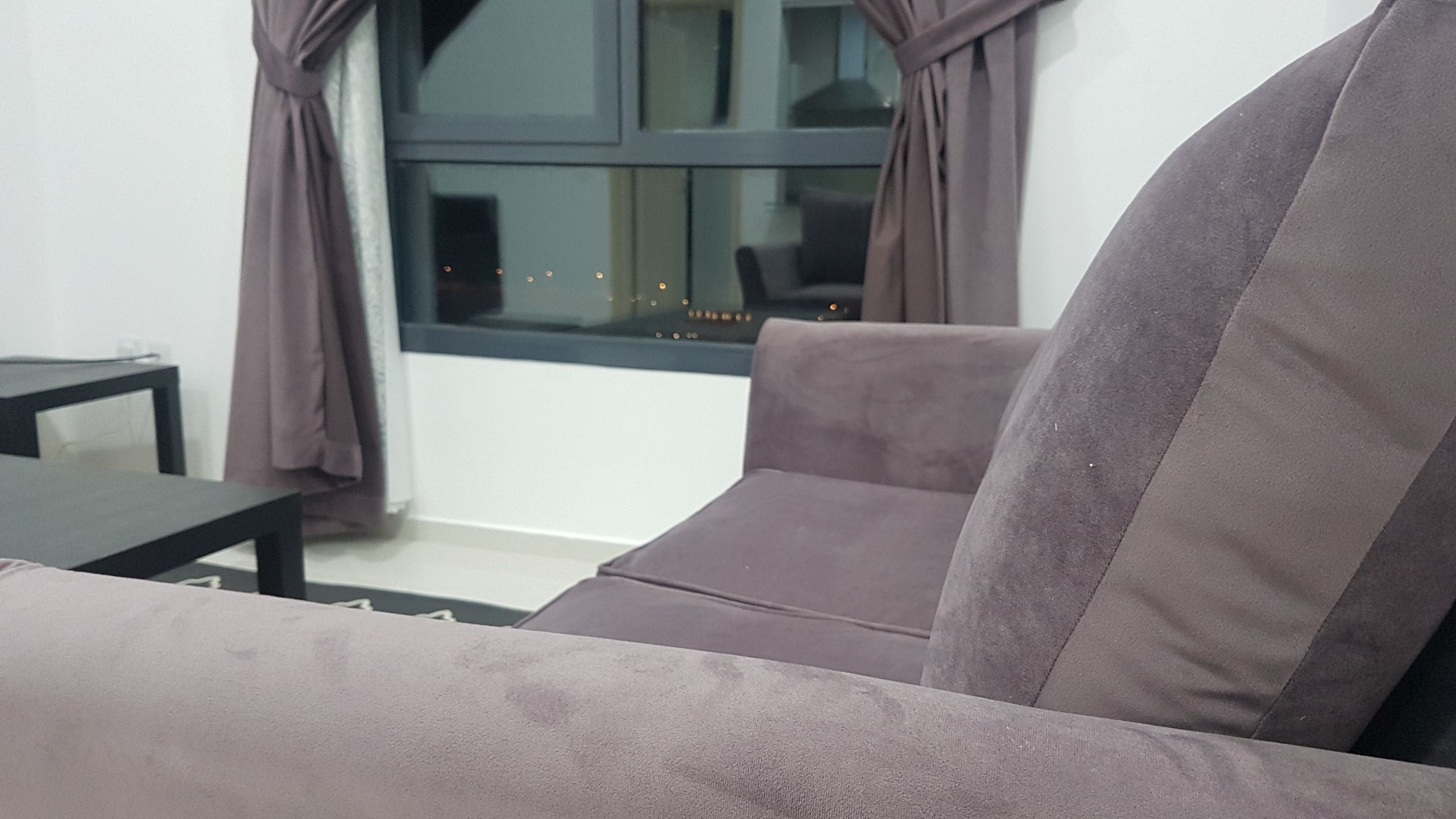 A living room with a sofa, a small table, and a window with curtains.