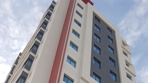 Un edificio de varios pisos con una llamativa banda vertical roja, grandes ventanales y un diseño arquitectónico moderno.