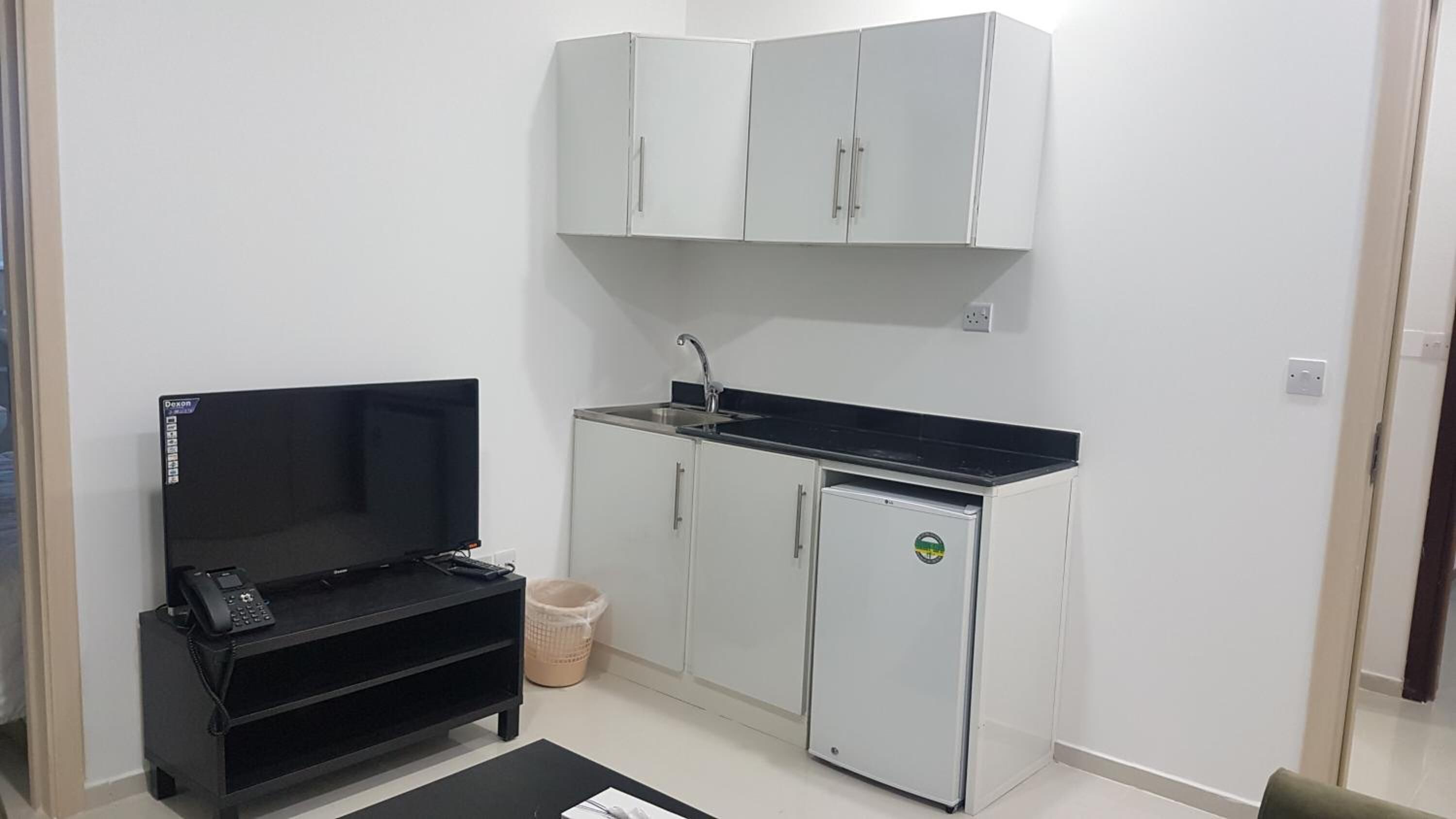 A compact kitchenette with a refrigerator, sink, and a small countertop.