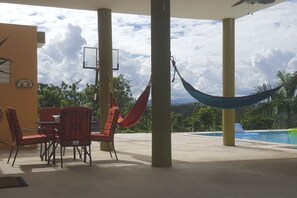 An outdoor seating area with a table and chairs, a hammock, and a pool.