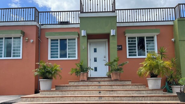 A building with a green facade, a white door, and a balcony with black railings.