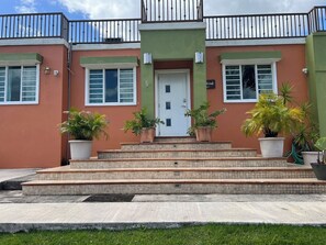 A building with a green facade, a white door, and a balcony with black railings.