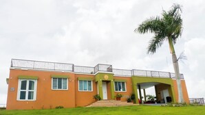 A two-story building with a flat roof, a balcony, and a covered entrance.