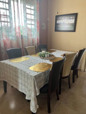 A dining area with a table set for four, chairs, a decorative centerpiece, and a framed picture on the wall.