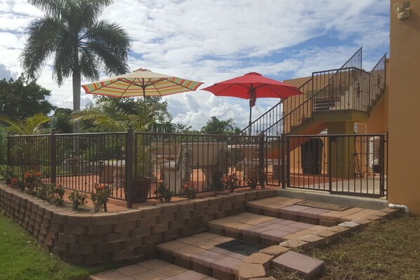 A courtyard with a brick wall, a metal gate, and two umbrellas.