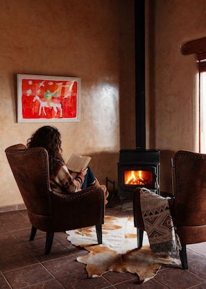 A cozy room with a fireplace, leather armchairs, a rug, and a painting on the wall.