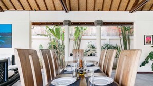 Comedor con una larga mesa de madera dispuesta para seis personas, rodeada de sillas de madera.