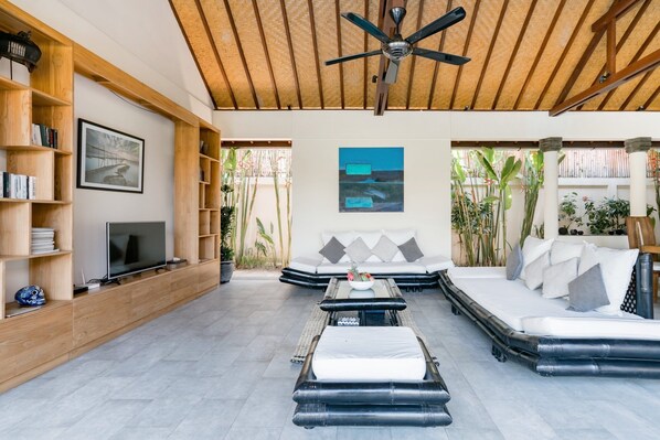 A modern living room with a TV, sofa, and a ceiling fan.