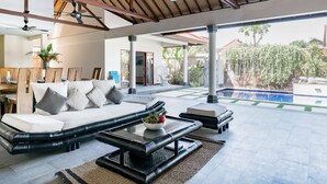 Un amplio espacio exterior con un sofá, una mesa de centro y una piscina al fondo.