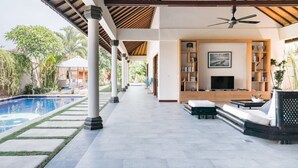Un espacio al aire libre cubierto con piscina, asientos y televisor.