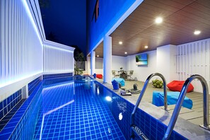 A swimming pool with a tiled floor, a metal ladder, and a seating area with a table and chairs. - Colorize Boutique Hotel (Koh Samui)