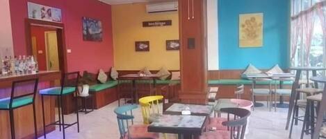A restaurant with a bar area, seating arrangements, and a ceiling fan.