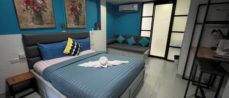 Un dormitorio moderno con cama, ventilador de techo, sofá y zona de comedor.