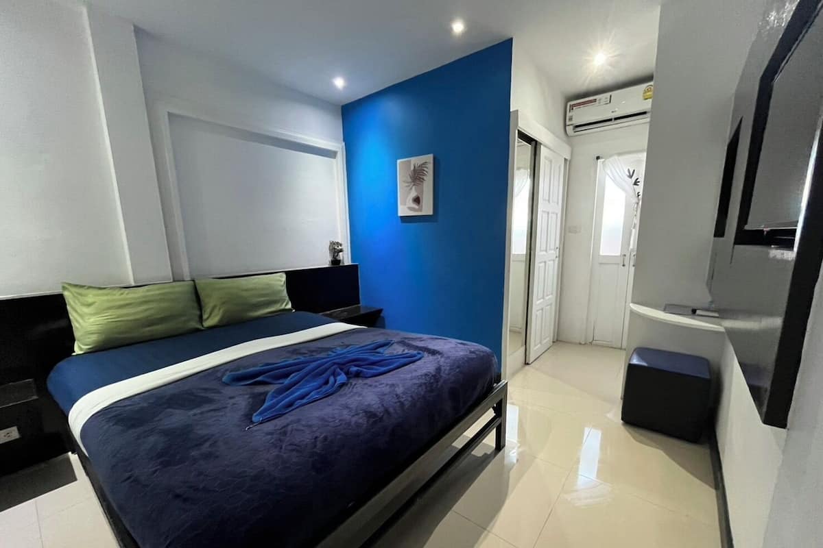A modern bedroom with a bed, a nightstand, a mirror, and an air conditioning unit.