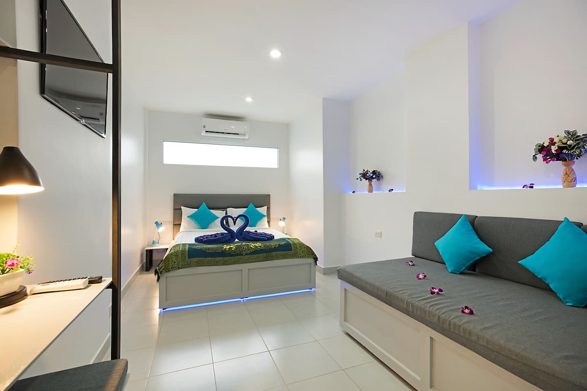 A modern bedroom with a bed, a sofa, and a desk.