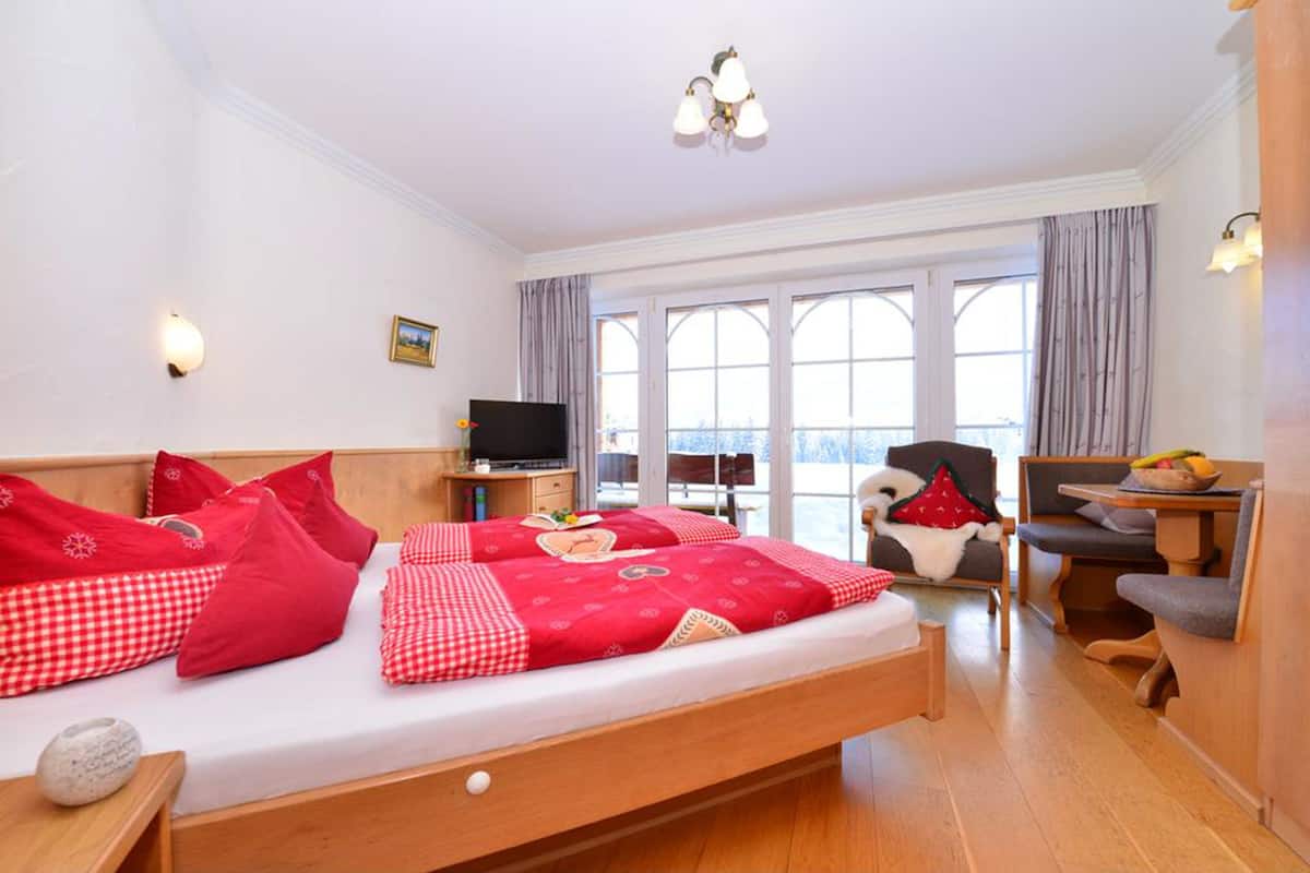 Quarto de hotel com uma cama grande, televisão, escrivaninha e cadeira.