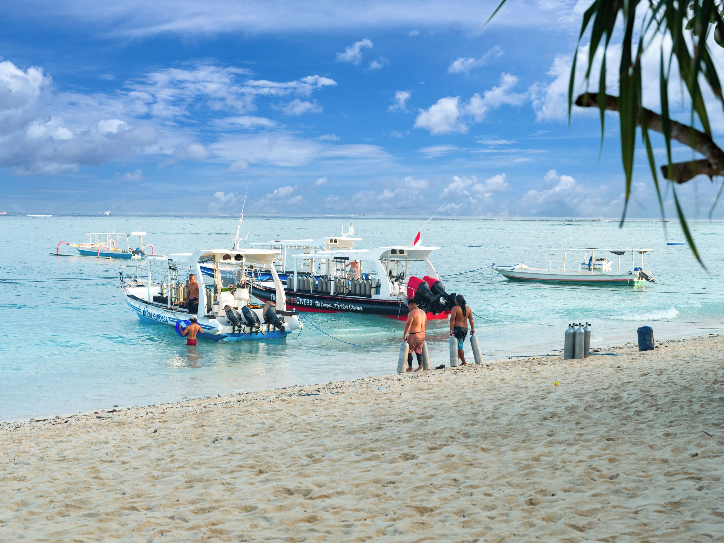 A beach with boats docked and people on the shore.