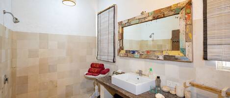 Un baño con tocador de madera, lavamanos y zona de ducha.