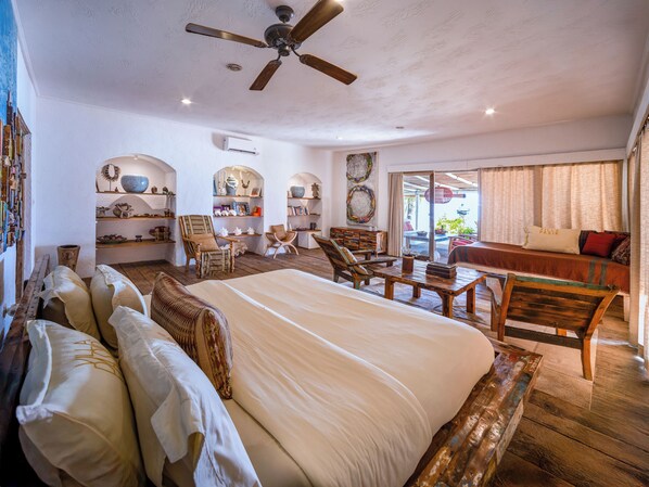 A spacious bedroom with a large bed, wooden furniture, and a ceiling fan. - Villa Pasir (Lembongan Island)